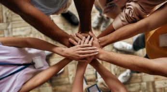 Close up above arms that are extended towards a circle in a "hands together" gesture